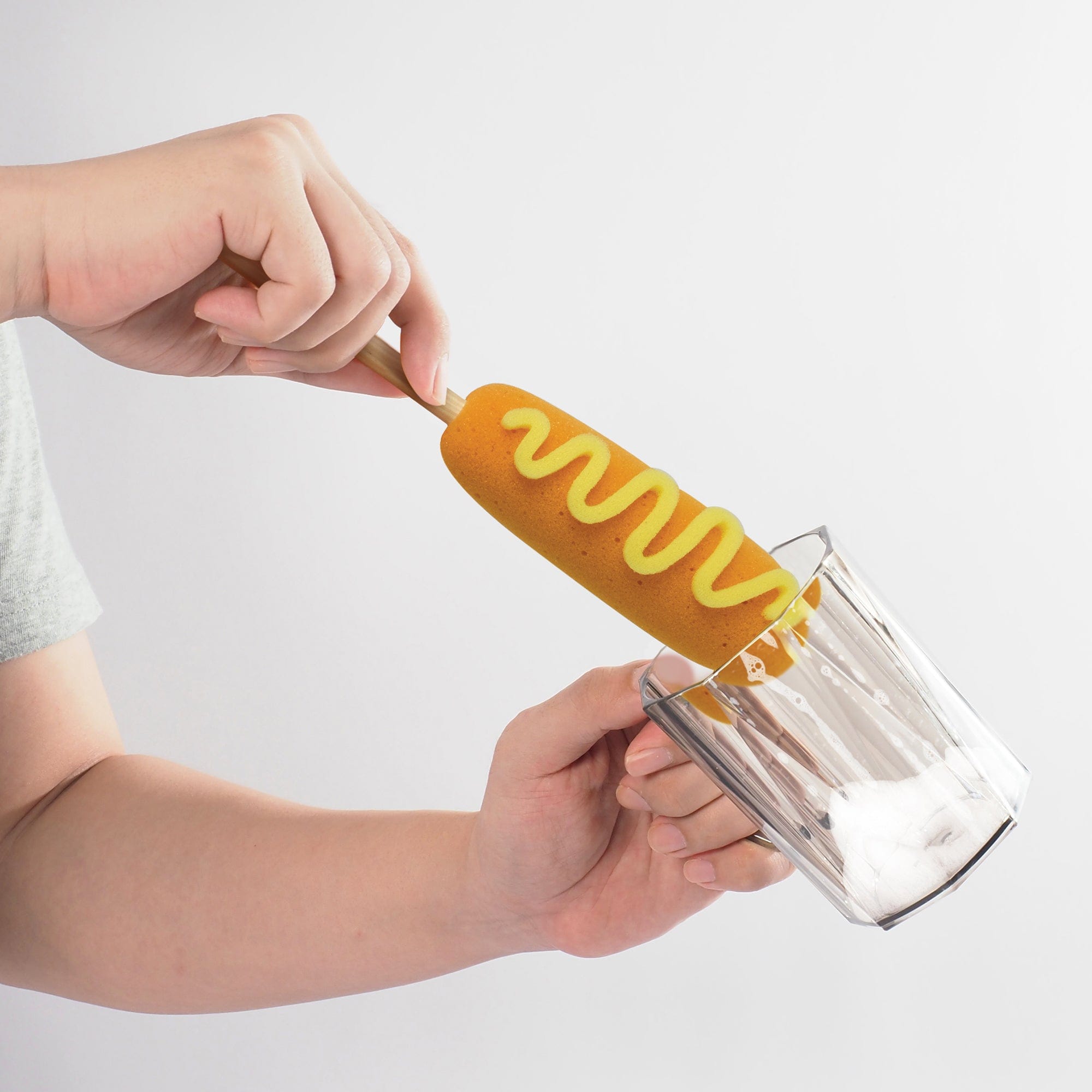 A bottle brush that looks like a corn dog cleaning a glass cup.