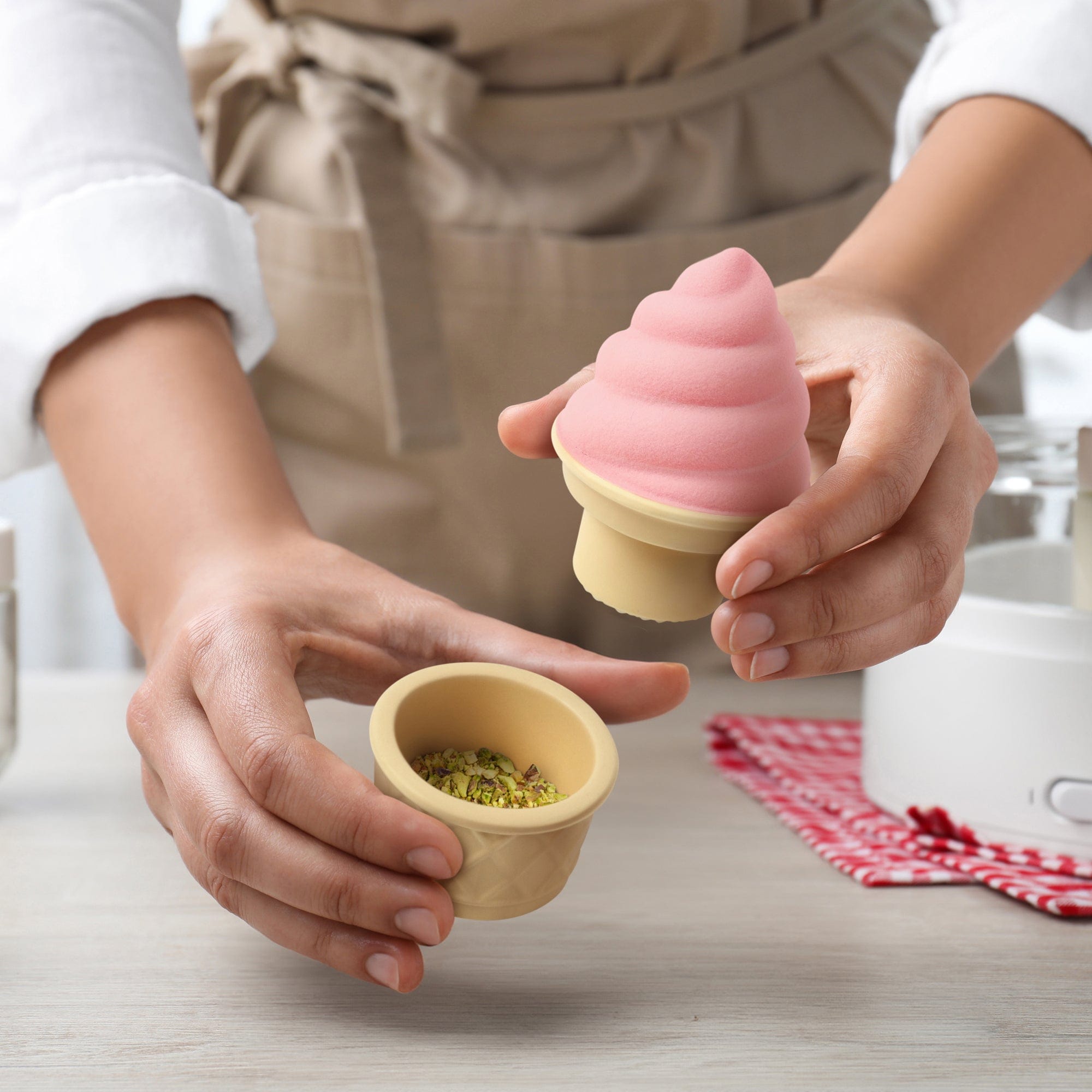 A ceramic spice and herb grinder that looks likes an ice cream cone. It is grinding nuts