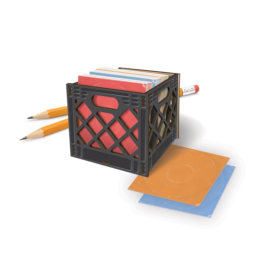 A small milk crate caddy for your desk. The crate is holding notecards that look like vinyl album covers in 4 colors: orange, blue, green, and red. There are two pencils behind the milk crate